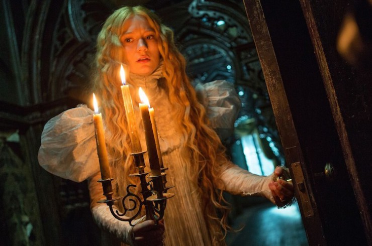 Mia Wasikowska as Edith, holding a candlabra in a darkened hall in Crimson Peak