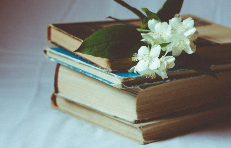 Photo of several hardcover books stacked with white flowers